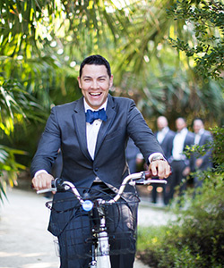 Groom riding bike down path on wedding day