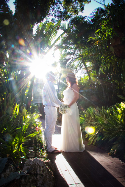 Married couple take pictures at a Key West resort with a burst of sunlight coming in behind them.