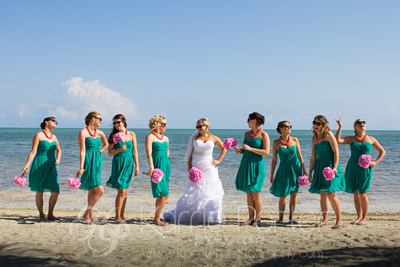 Bridal party in seafoam green dresses chat on the beach