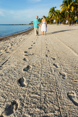 Couple walks through sand leaving footprints on Smathers Beach