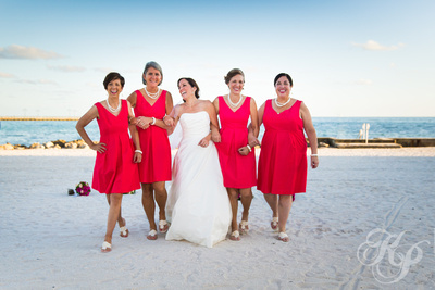 Bridesmaids link arms and walk along Rest Beach near White Street Pier.