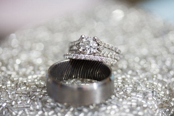 Wedding rings showing groom's fingerprint inside and sparkle background.